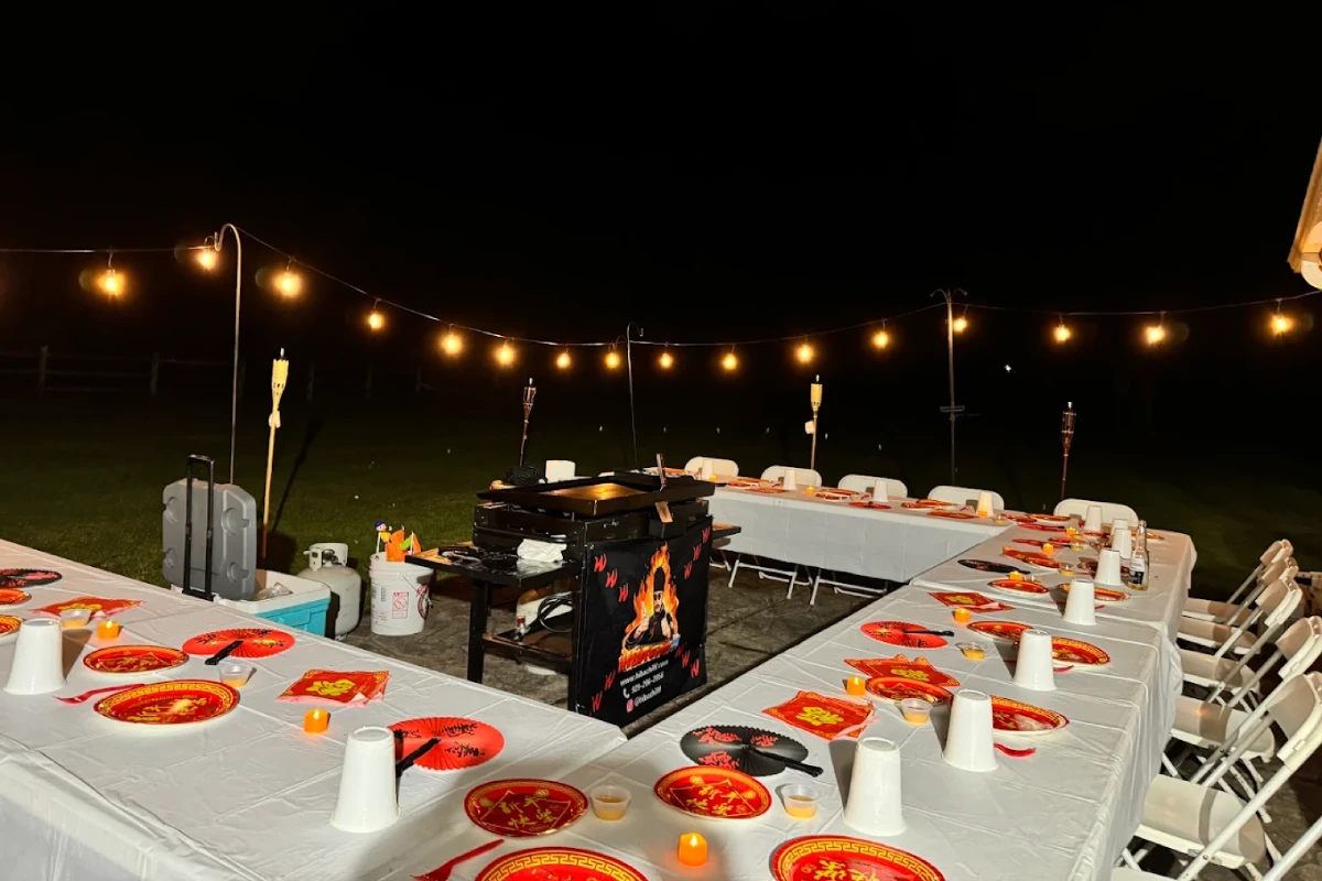 Evening hibachi at home setup with dining tables, outdoor lighting, and a private chef cooking station