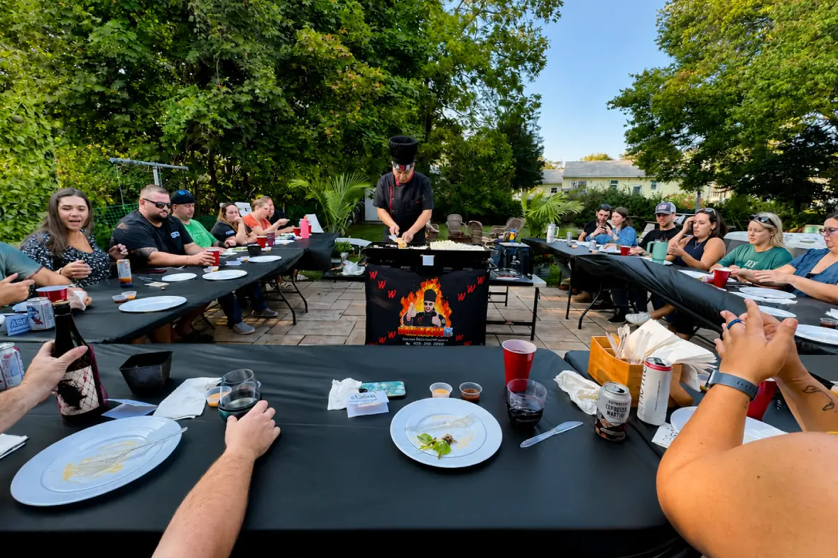 Guests enjoying a backyard hibachi dinner with live chef cooking