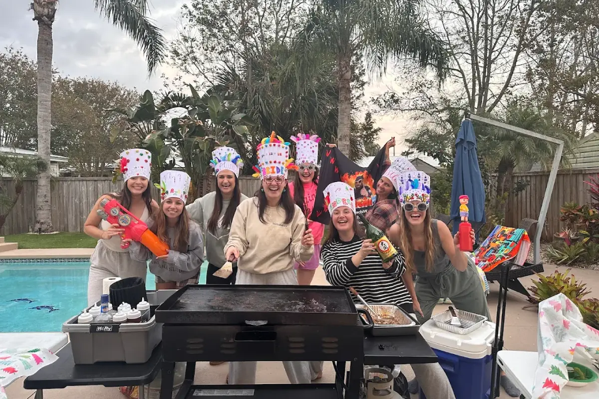 Guests wearing festive birthday chef hats during a backyard hibachi party by the pool